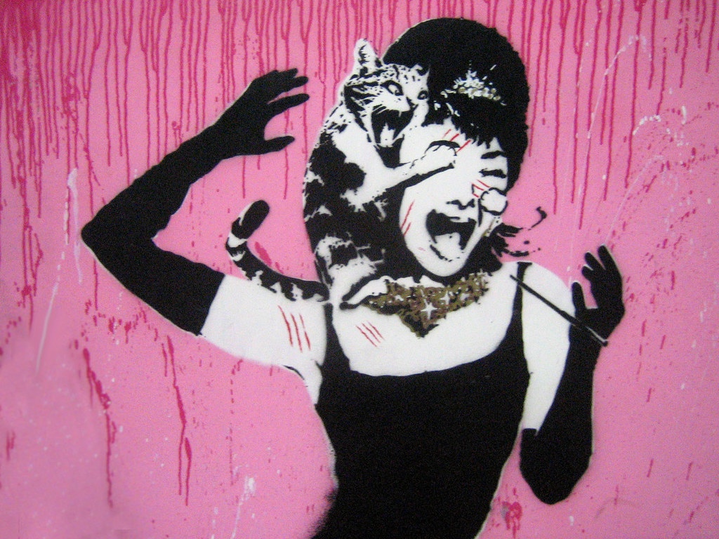 Black and white stencil on pink background of Holly Golightly’s face being attacked by a tabby cat